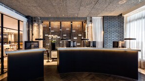 Un espace d’accueil moderne avec un comptoir incurvé, un mur en briques et un motif de parquet en chevrons.