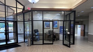 A hotel reception area with a glass partition, a reception desk, and a digital kiosk.