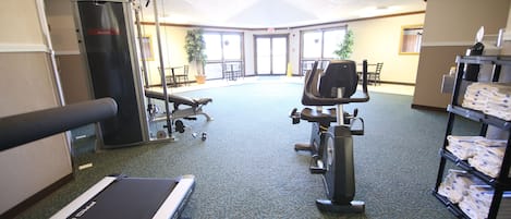 Un gimnasio con equipo de ejercicio, cinta de correr y estación de agua.