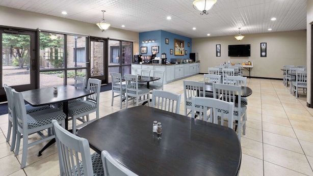 A dining area with tables and chairs, a kitchen area, and a TV mounted on the wall.