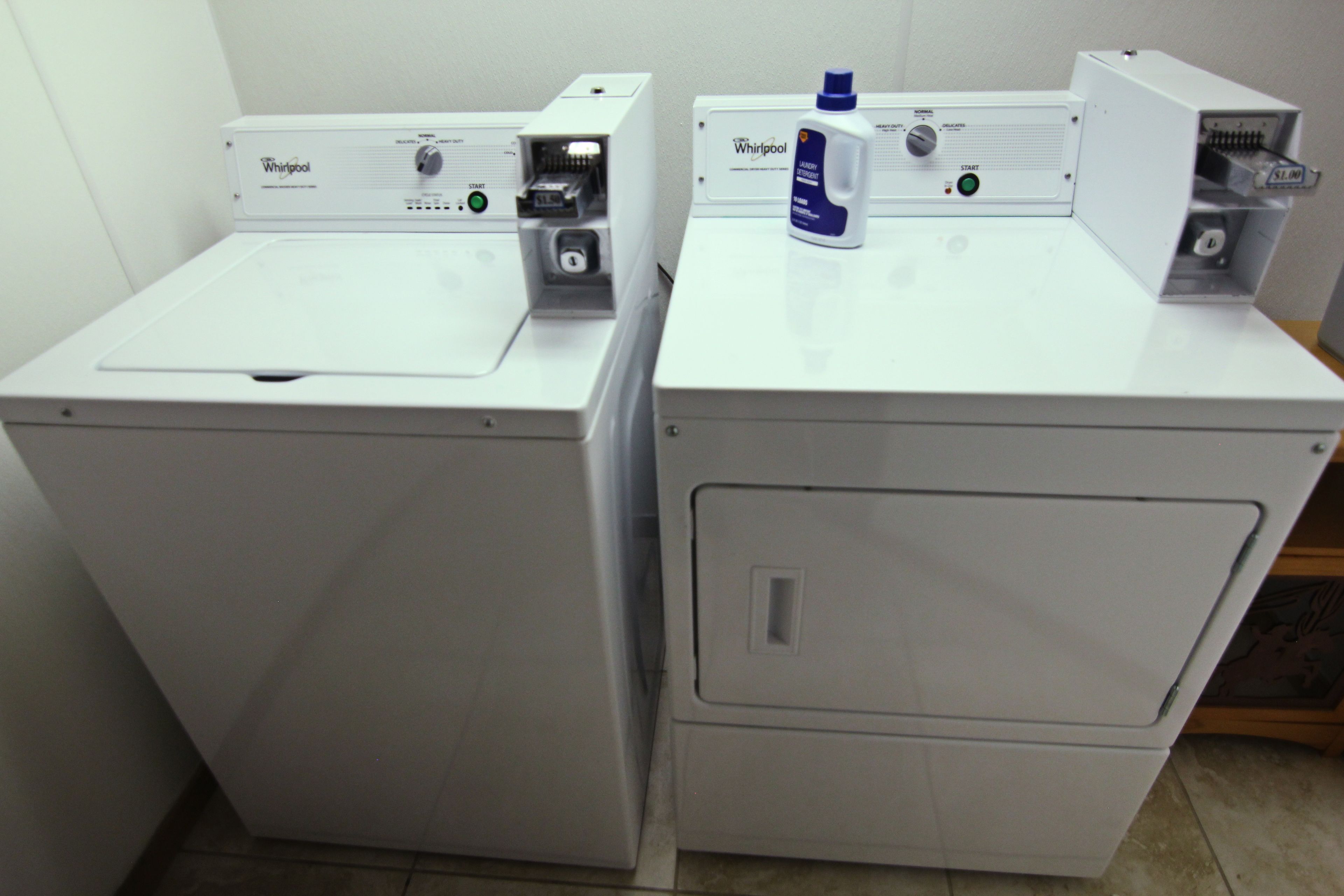 Two Whirlpool front-loading washing machines in a laundry room.