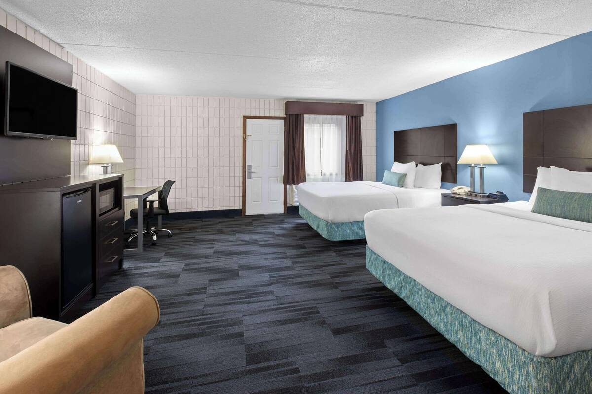 Een hotelkamer met twee bedden, een bureau, een televisie en een stoel.