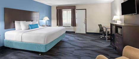Een hotelkamer met een groot bed, een bureau met stoel, een televisie en een deur naar de badkamer.