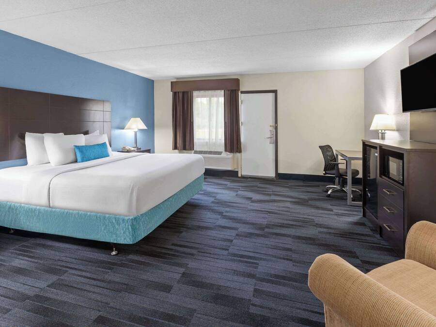 Una habitación de hotel con una cama grande, un escritorio con silla, un televisor y una puerta que da a un baño.