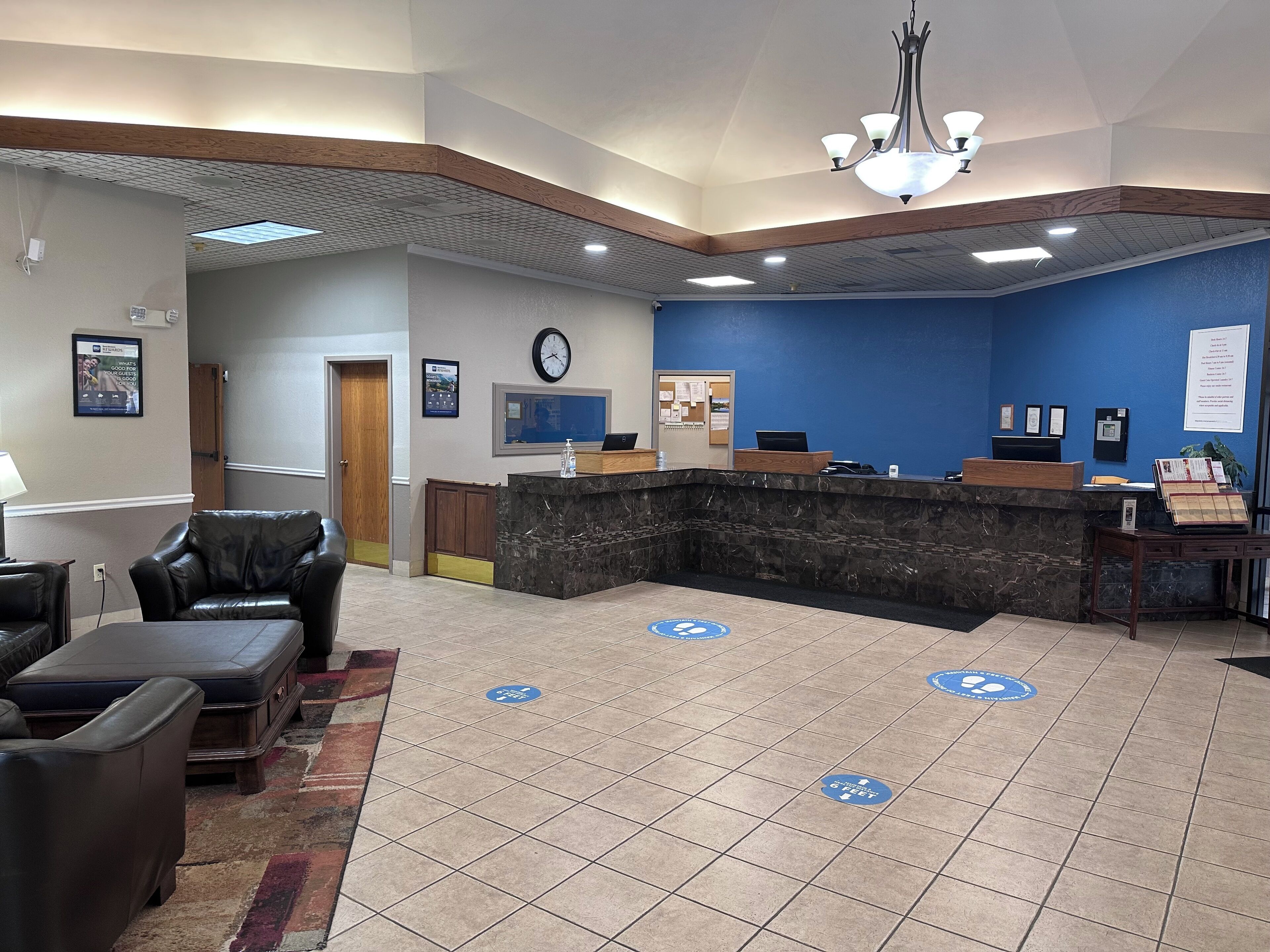A hotel lobby with a reception desk, seating area, and a clock on the wall.