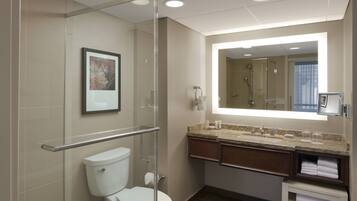 A modern bathroom with a glass shower enclosure, a toilet, a sink with a vanity, and a large mirror.