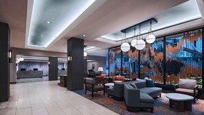 A modern lobby with a reception desk, seating area, and a large abstract wall mural. - Houston Marriott Medical Center/Museum District (Houston)