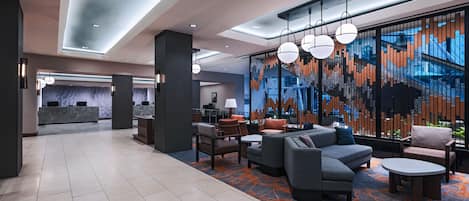 A modern lobby with a reception desk, seating area, and a large abstract wall mural.