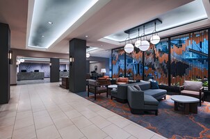 A modern lobby with a reception desk, seating area, and a large abstract wall mural.