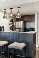 A modern kitchen with a central island, stainless steel appliances, and pendant lighting.