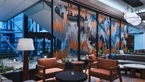 A modern lounge area with a sofa, chairs, and a round table. A decorative wall with vertical elements is visible. - Houston Marriott Medical Center/Museum District (Houston)