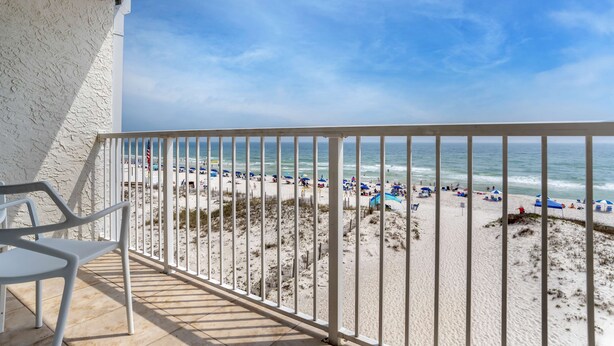 A balcony with a view of a beach, featuring a white railing and a single white chair. - Best Western On The Beach (Gulf Shores)