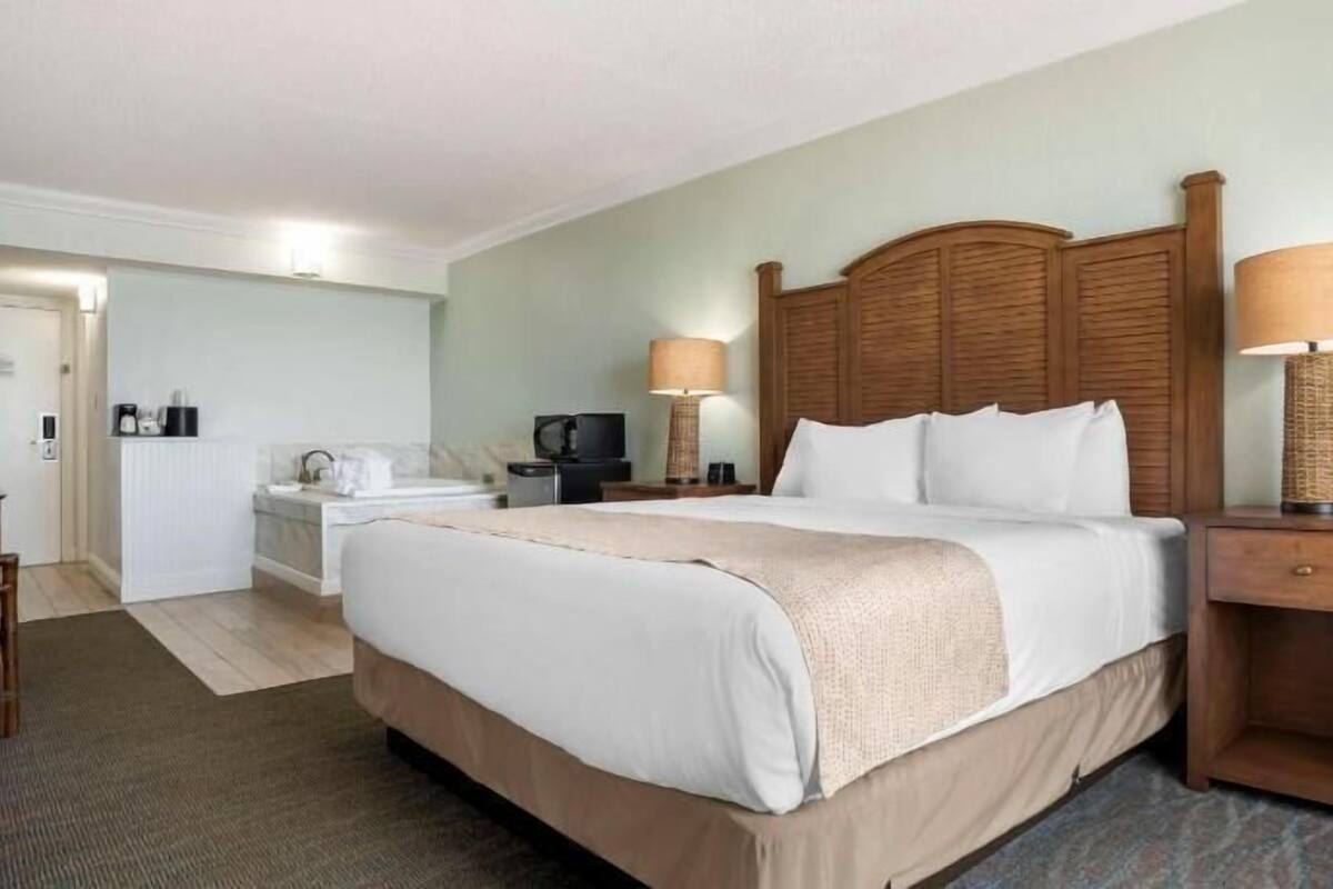 A hotel room with a bed, bedside tables, a desk, and a chair.