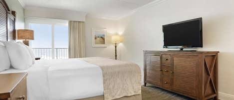 A hotel room with a large bed, a television on a wooden cabinet, and a window with curtains.