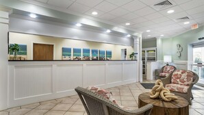 A reception area with a counter, seating, and artwork on the wall. - Best Western On The Beach (Gulf Shores)