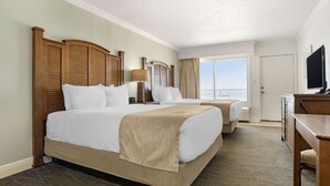 A hotel room with two beds, a TV, a desk, and a balcony with a view. - Best Western On The Beach (Gulf Shores)