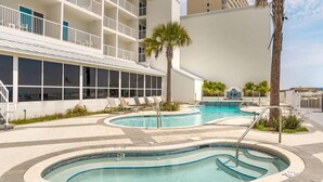 A hotel with a pool area featuring multiple swimming pools, lounge chairs, and palm trees. - Best Western On The Beach (Gulf Shores)