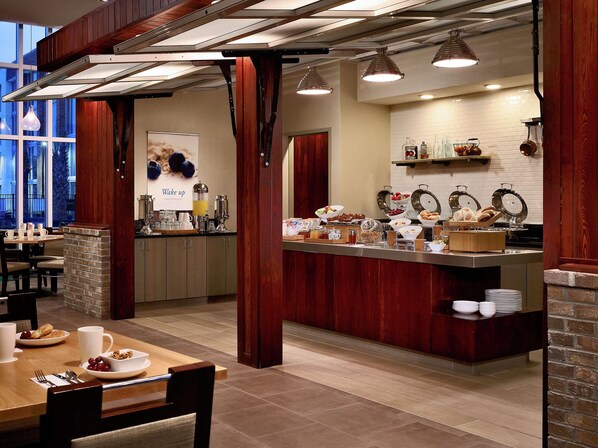 A breakfast area with a buffet setup, including various food items and a coffee station.