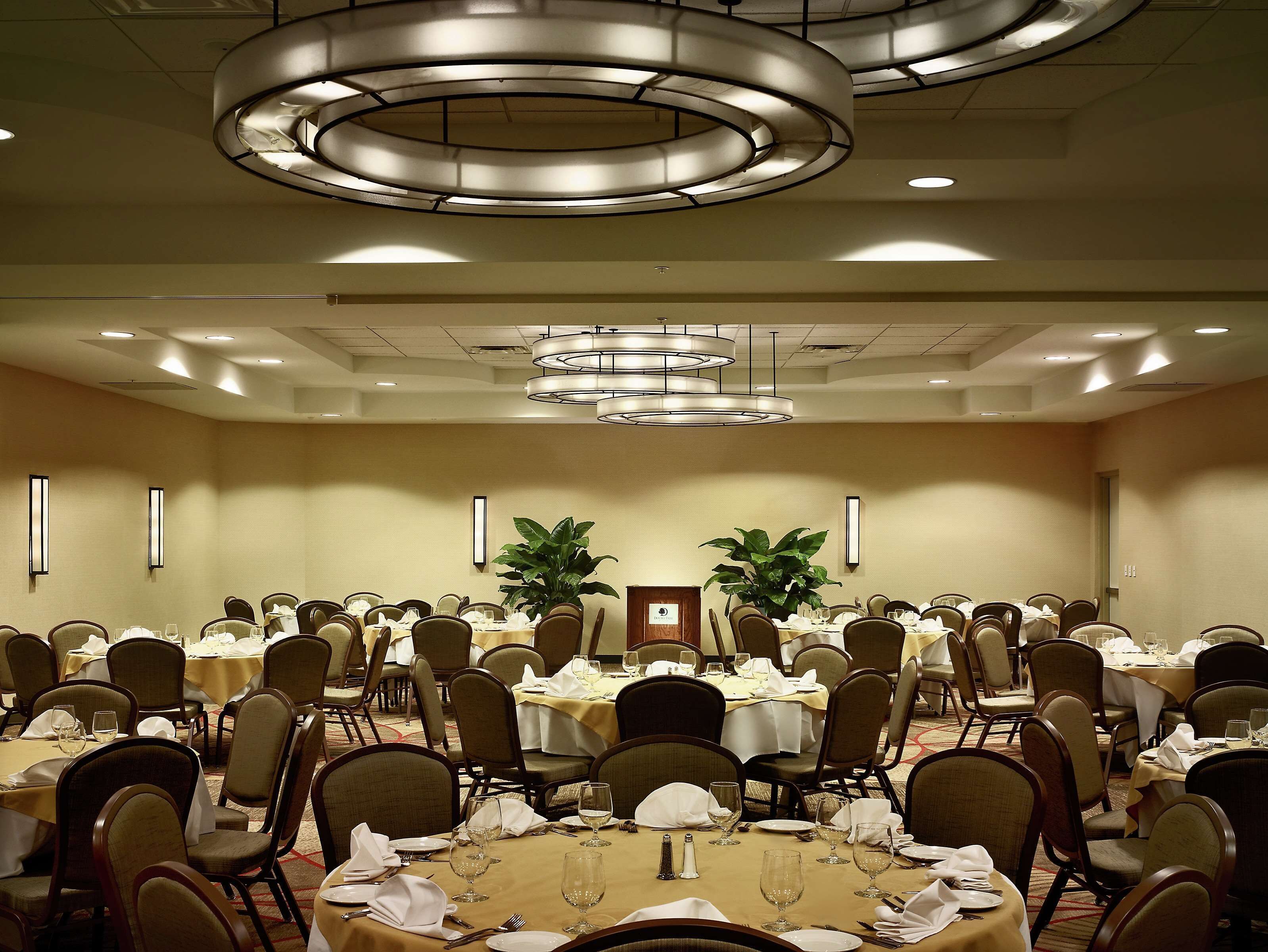 Un salón de banquetes con varias mesas redondas dispuestas para comer, equipado con sillas y vajilla.
