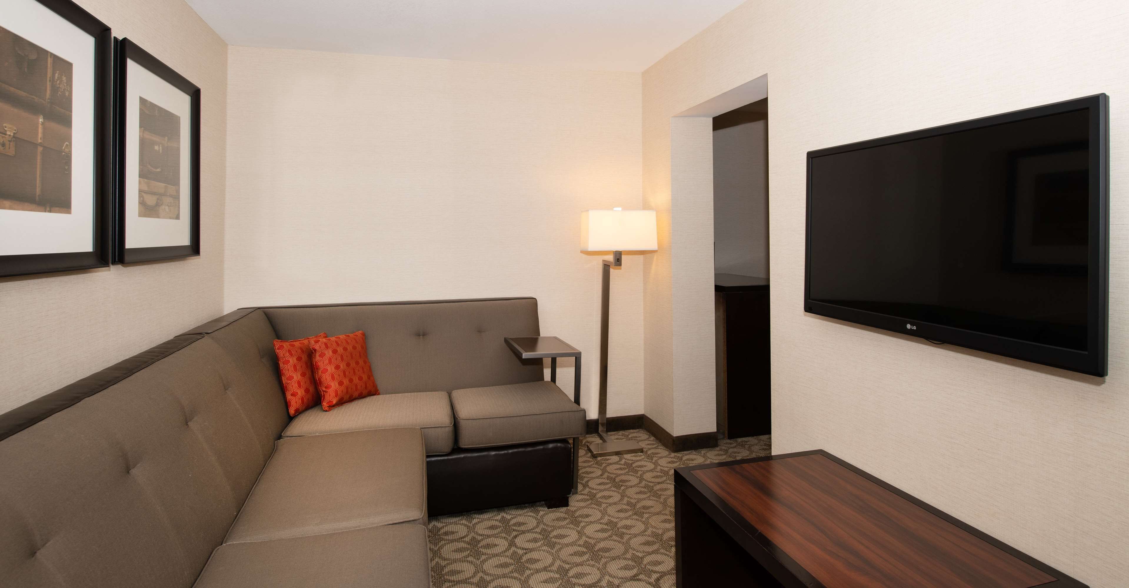 Une chambre d’hôtel avec un canapé, une télévision, une lampe et des tableaux encadrés au mur.