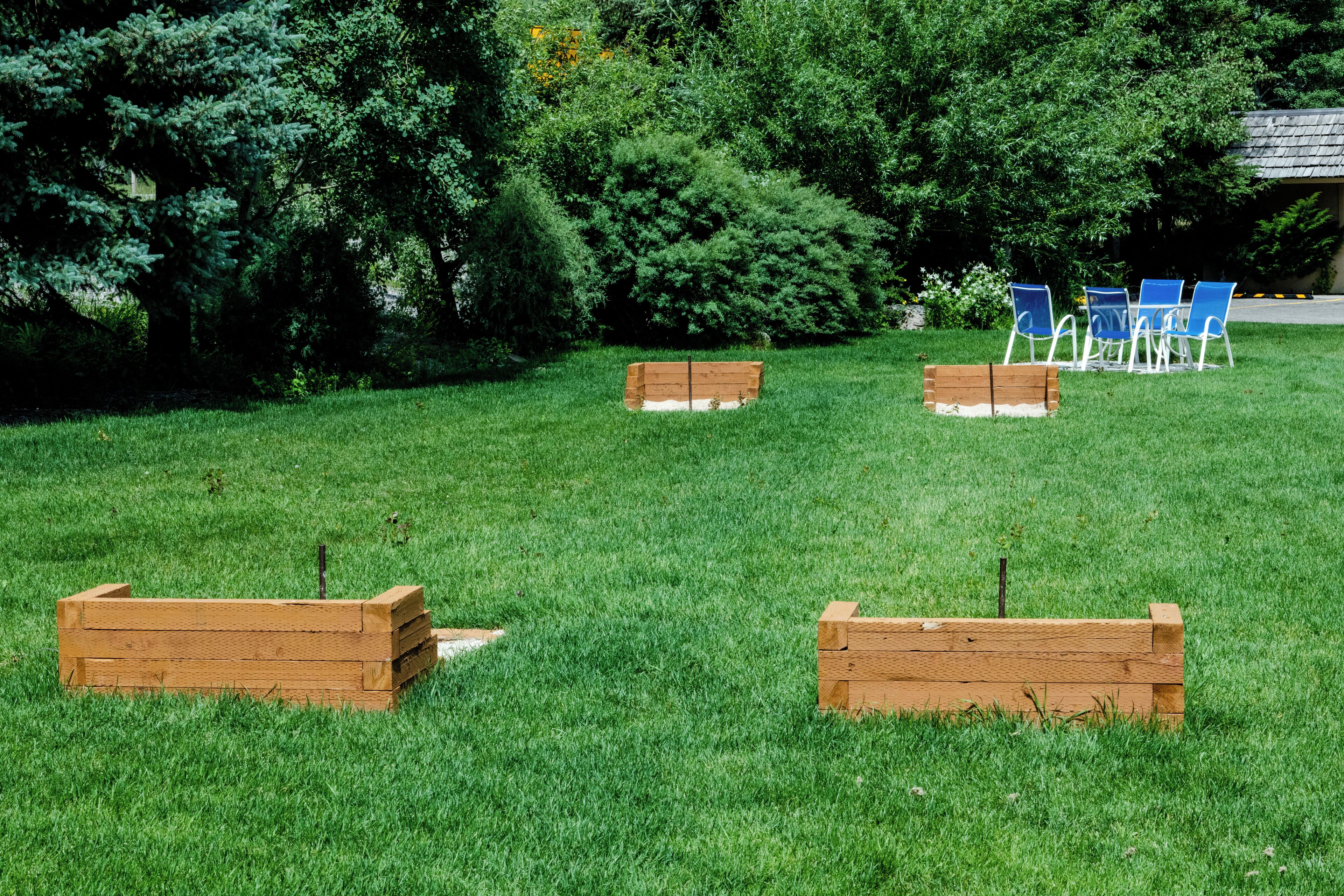 Un'area verde all'aperto con fioriere in legno e sedie blu.