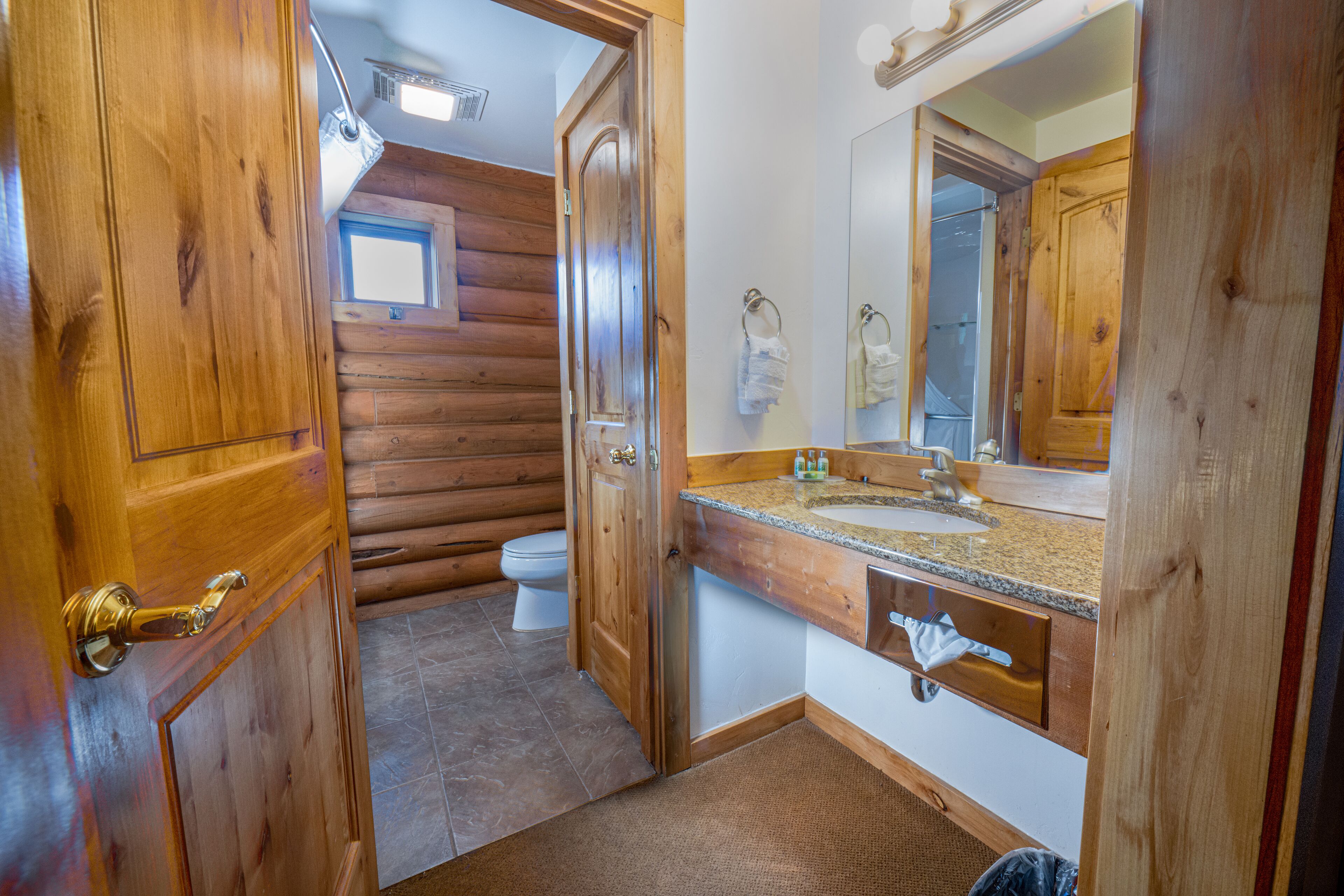 Ein Badezimmer einer Holzhütte mit Toilette, Waschbecken und Spiegel.