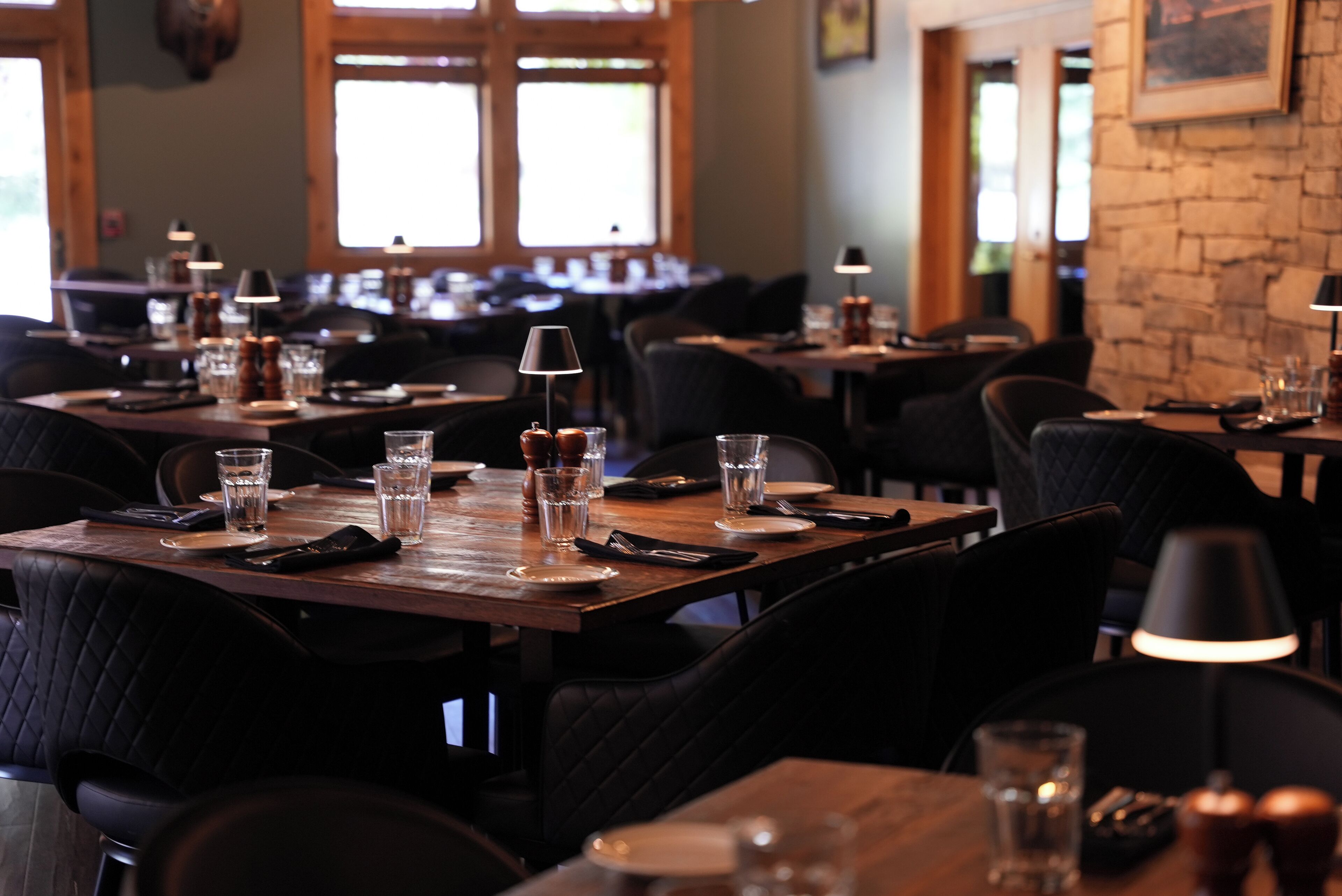 A restaurant interior with multiple tables, chairs, and dining tables set with plates, glasses, and cutlery.