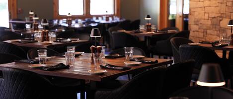 A restaurant interior with multiple tables, chairs, and dining tables set with plates, glasses, and cutlery.