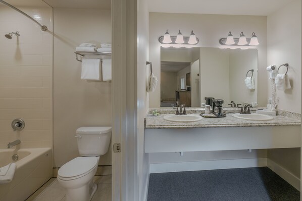 Une salle de bain équipée de toilettes, d’un lavabo, d’un miroir et d’une douche.