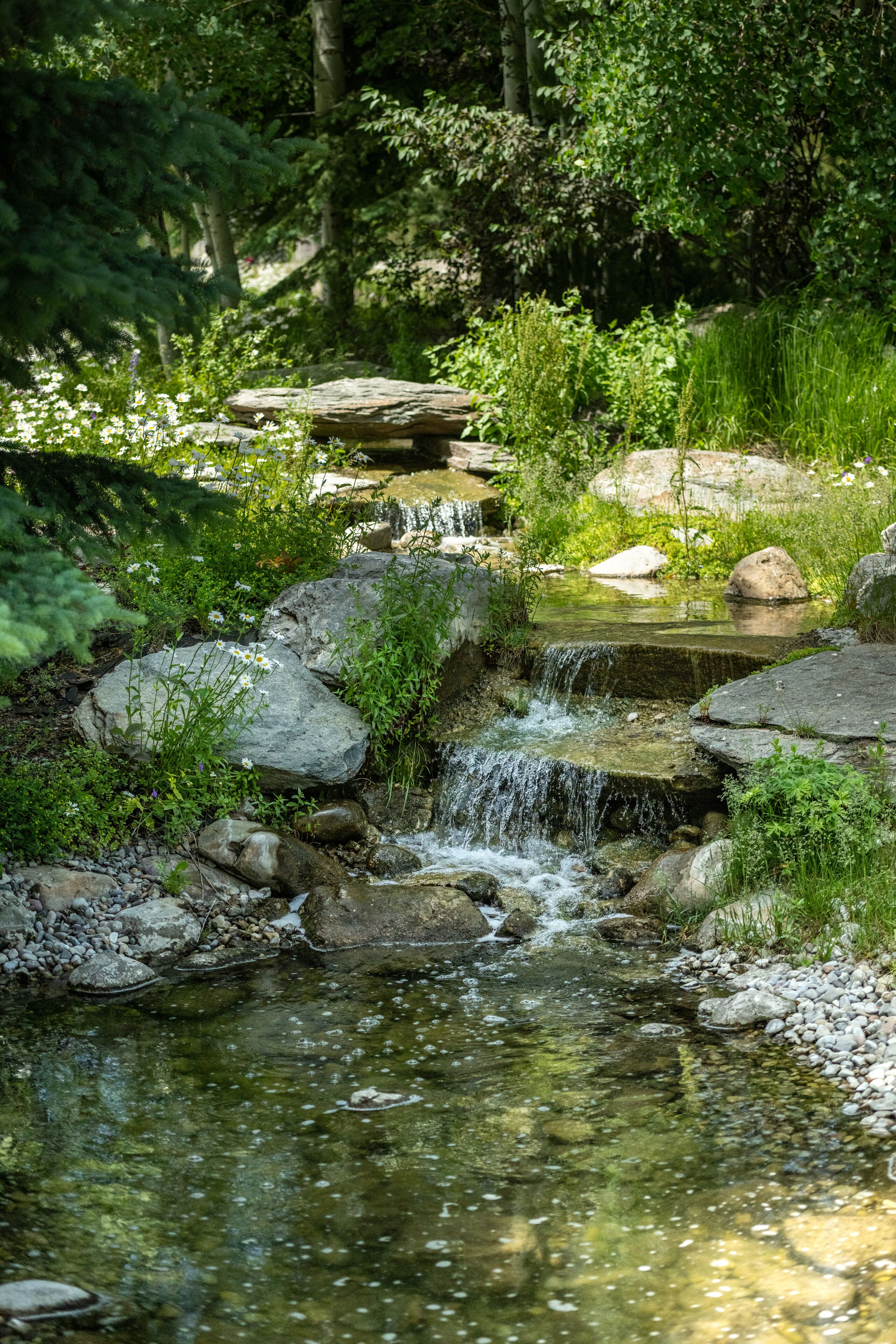 A small waterfall in a natural setting with rocks and greenery.