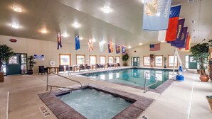 A swimming pool area with multiple flags, a hot tub, and a seating area with tables and chairs. - Flying Saddle Resort (Alpine)