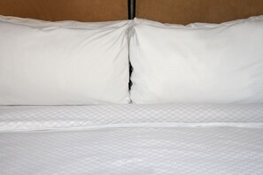 A neatly made bed with white bedding and a checkered mattress cover. - Four Points by Sheraton Philadelphia Northeast (Philadelphia)