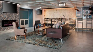 A modern living room with a large flat-screen TV, a fireplace, a map wall, and a bar area. - Four Points by Sheraton Philadelphia Northeast (Philadelphia)