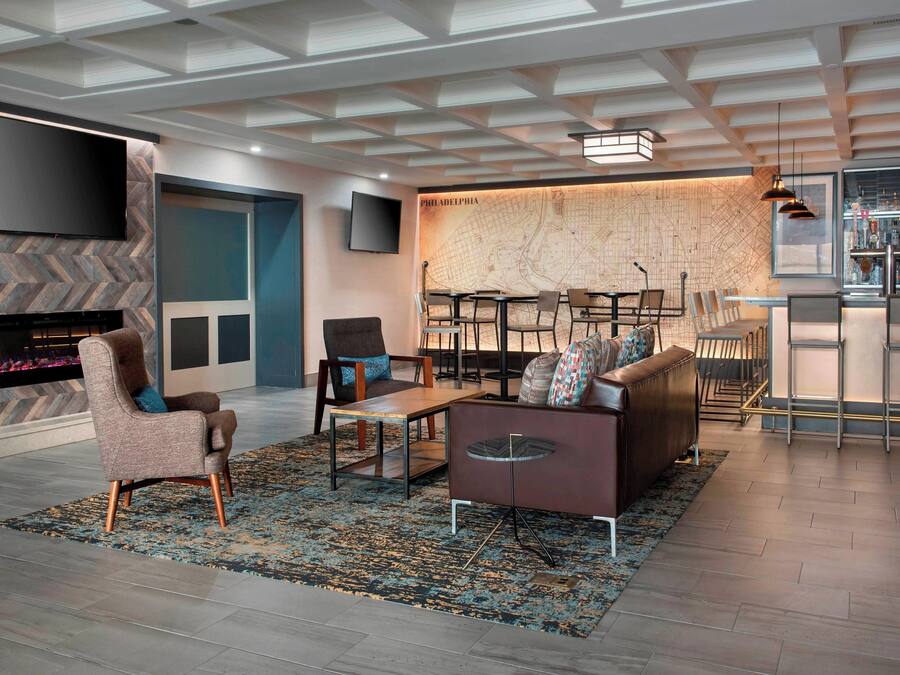 A modern living room with a large flat-screen TV, a fireplace, a map wall, and a bar area.