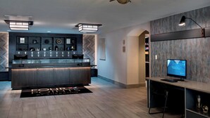 A modern bar area with a counter, shelves with various items, and a television on a desk. - Four Points by Sheraton Philadelphia Northeast (Philadelphia)
