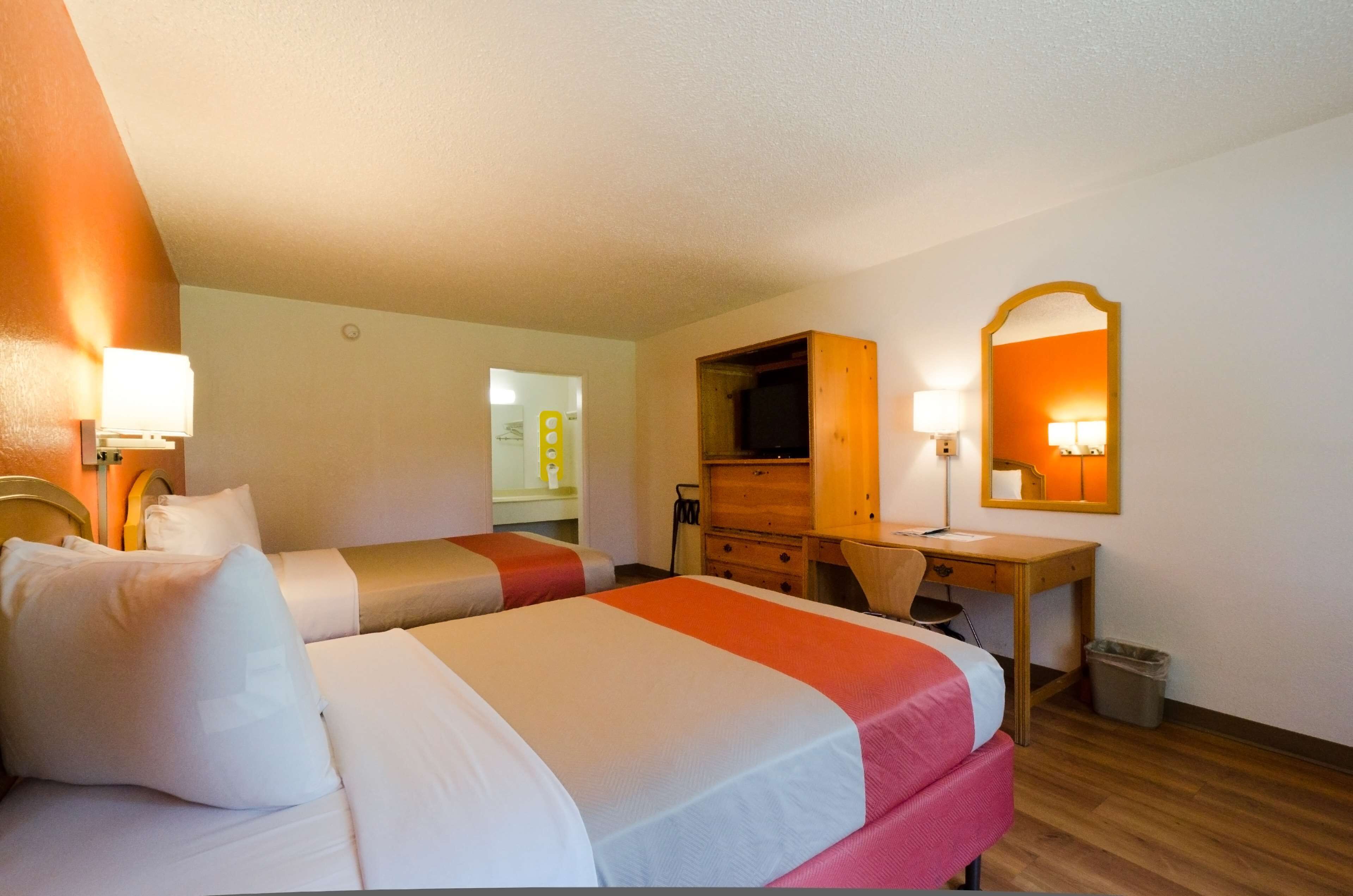 Una habitación de hotel con dos camas, un escritorio, un espejo y un televisor.