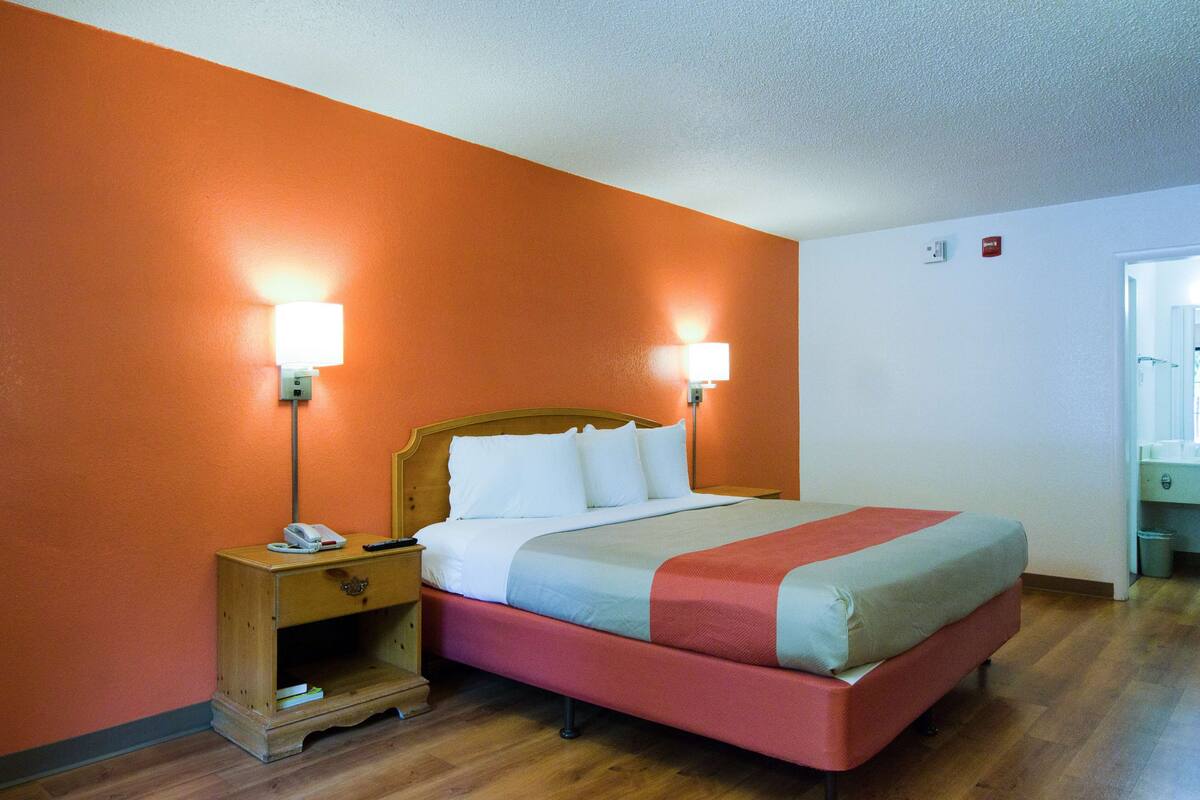 Ein Hotelzimmer mit einem hölzernen Bett, zwei Nachttischlampen, einem Nachttisch und Holzboden.