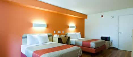 A hotel room with two beds, a desk, a chair, a microwave, and a door.