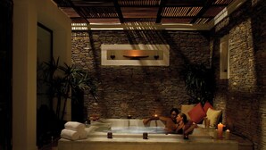 A stone-walled room with a bathtub, candles, and towels. - Hilton Luxor Resort & Spa (Luxor)