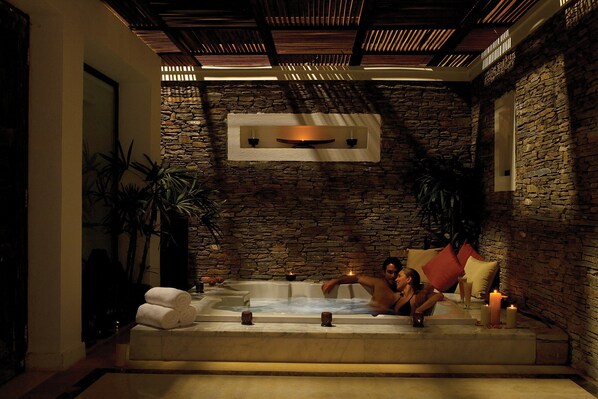 A stone-walled room with a bathtub, candles, and towels. - Hilton Luxor Resort & Spa (Luxor)