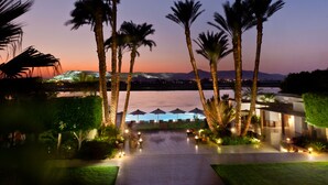 A resort with a pool area, palm trees, and a view of the mountains at dusk. - Hilton Luxor Resort & Spa (Luxor)