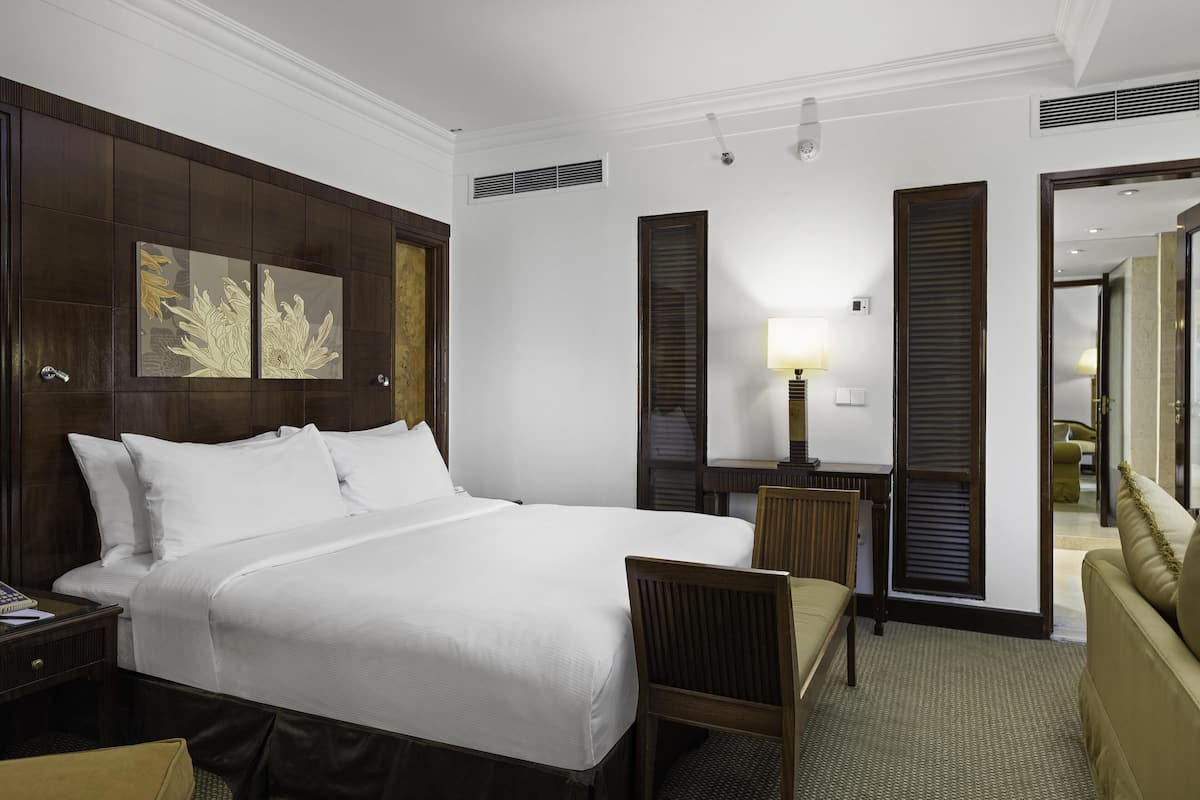 A hotel room with a large bed, a desk, a chair, and a sofa.