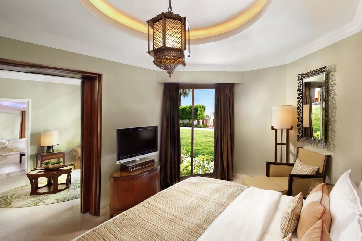 A hotel room with a bed, television, and a view of the outdoors.
