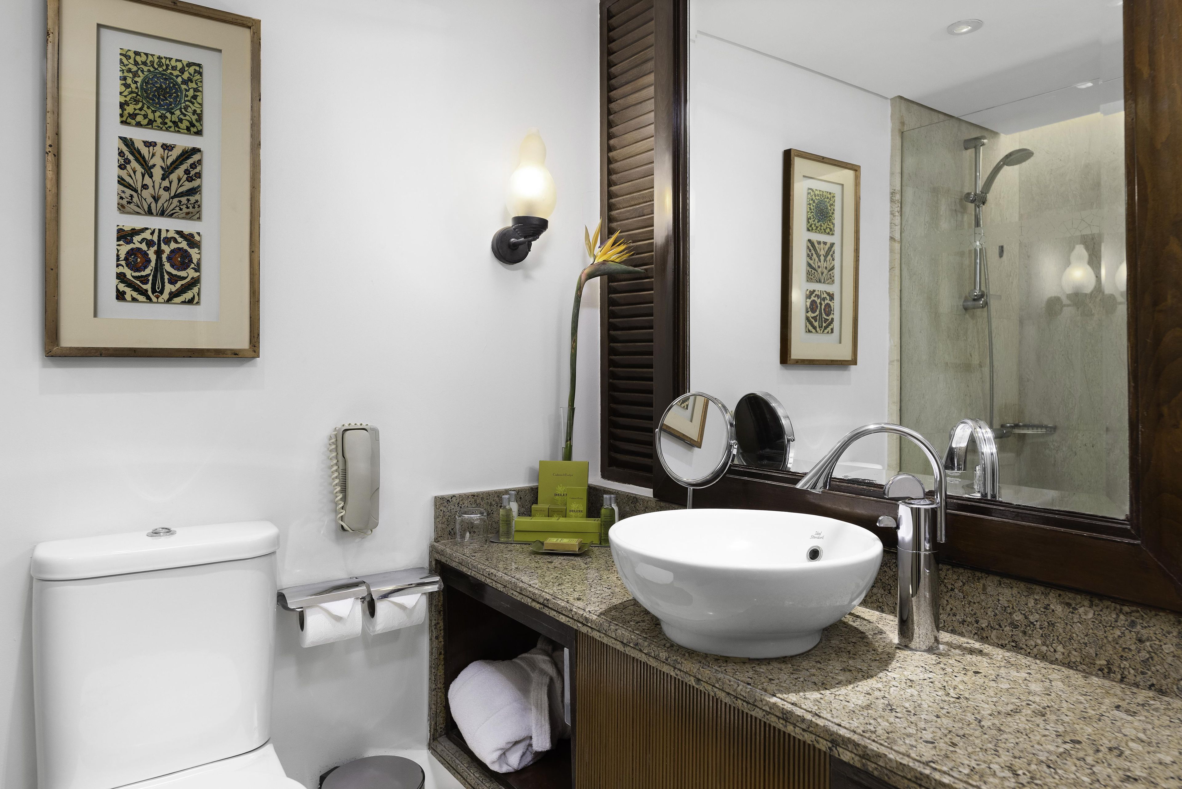 A bathroom with a white sink, a mirror, a toilet, and a shower.