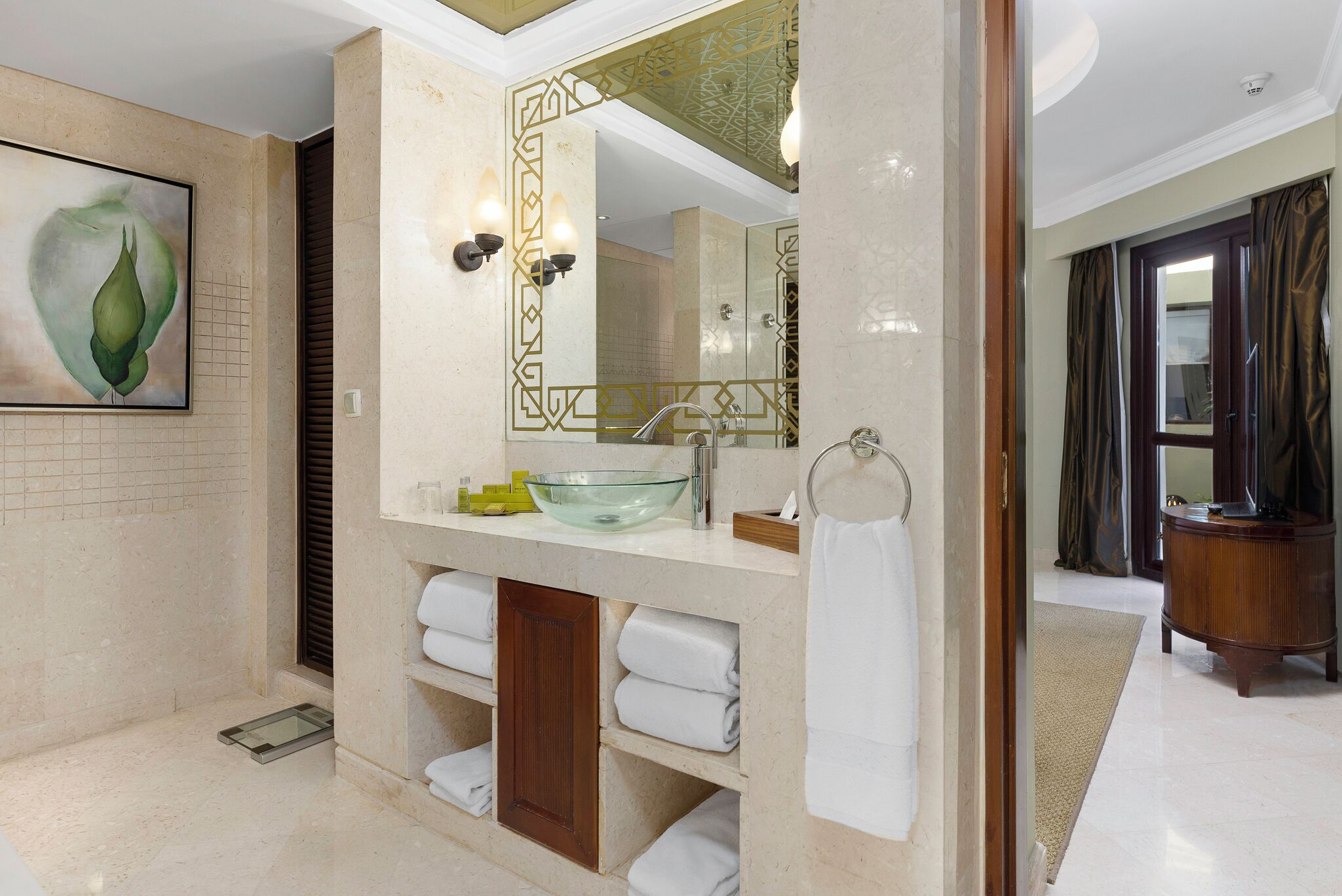 A modern bathroom with a glass sink, a large mirror, and a towel rack.
