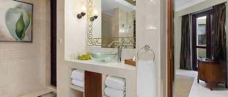 A modern bathroom with a glass sink, a large mirror, and a towel rack.