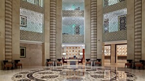 A spacious lobby with a central reception desk, patterned floor, and decorative lattice windows. - Hilton Luxor Resort & Spa (Luxor)
