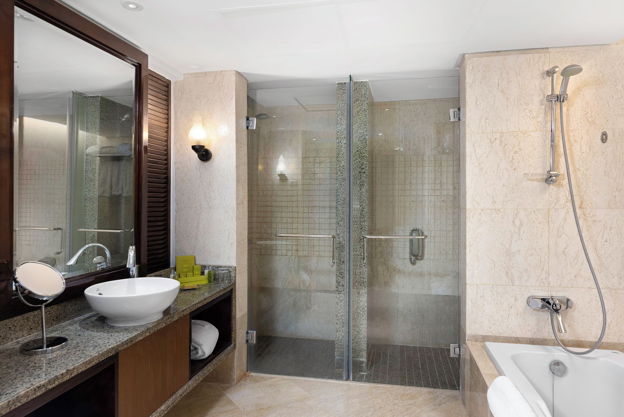 A modern bathroom with a glass-enclosed shower, a white sink, and a large mirror.
