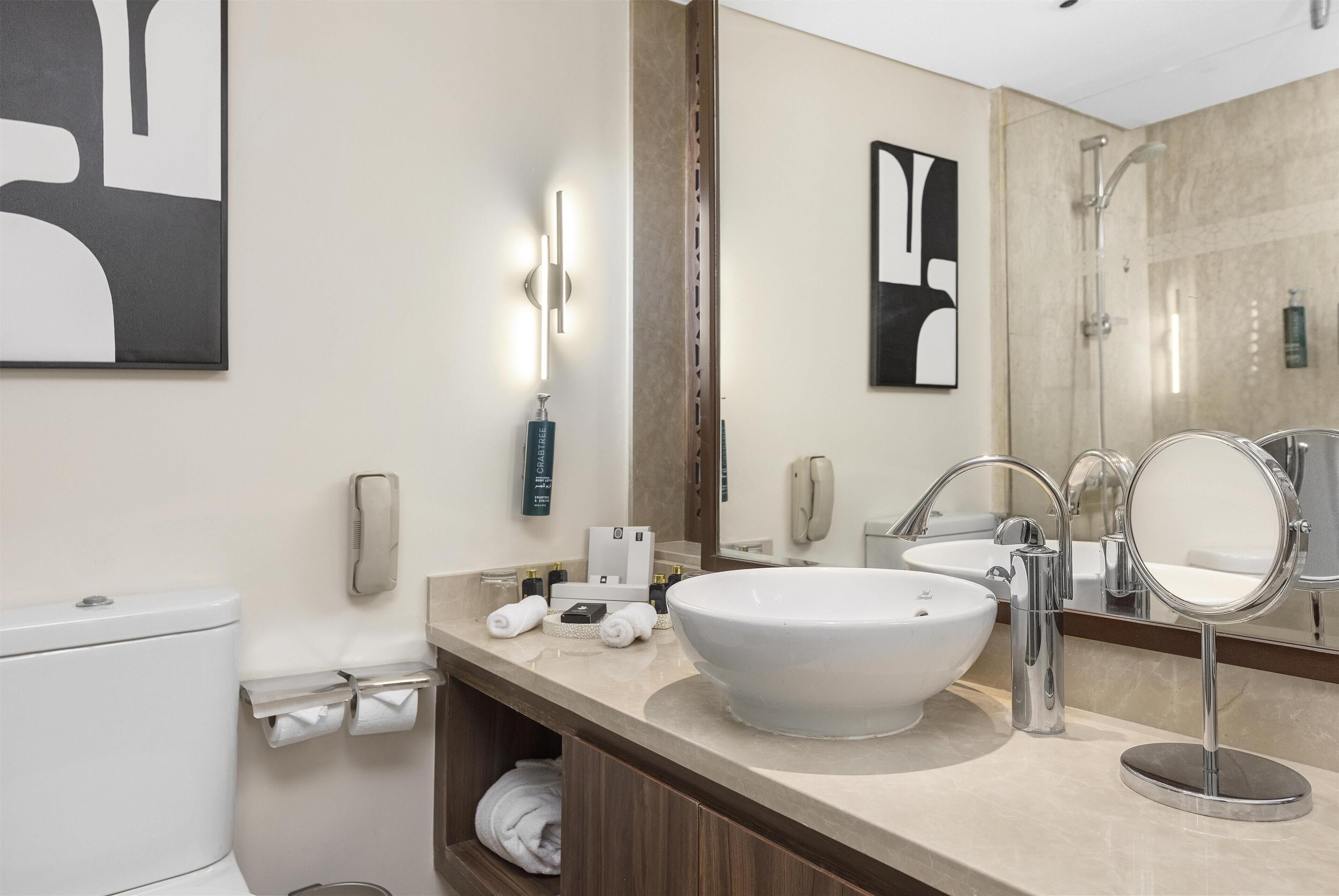 Une salle de bain moderne avec un grand lavabo blanc, un miroir, des toilettes et une douche.