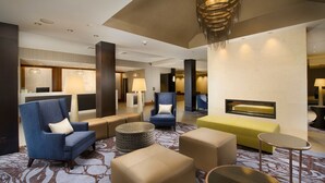 A hotel lobby with seating arrangements, a reception desk, and a fireplace. - Skybridge Seattle Airport Hotel (SeaTac)